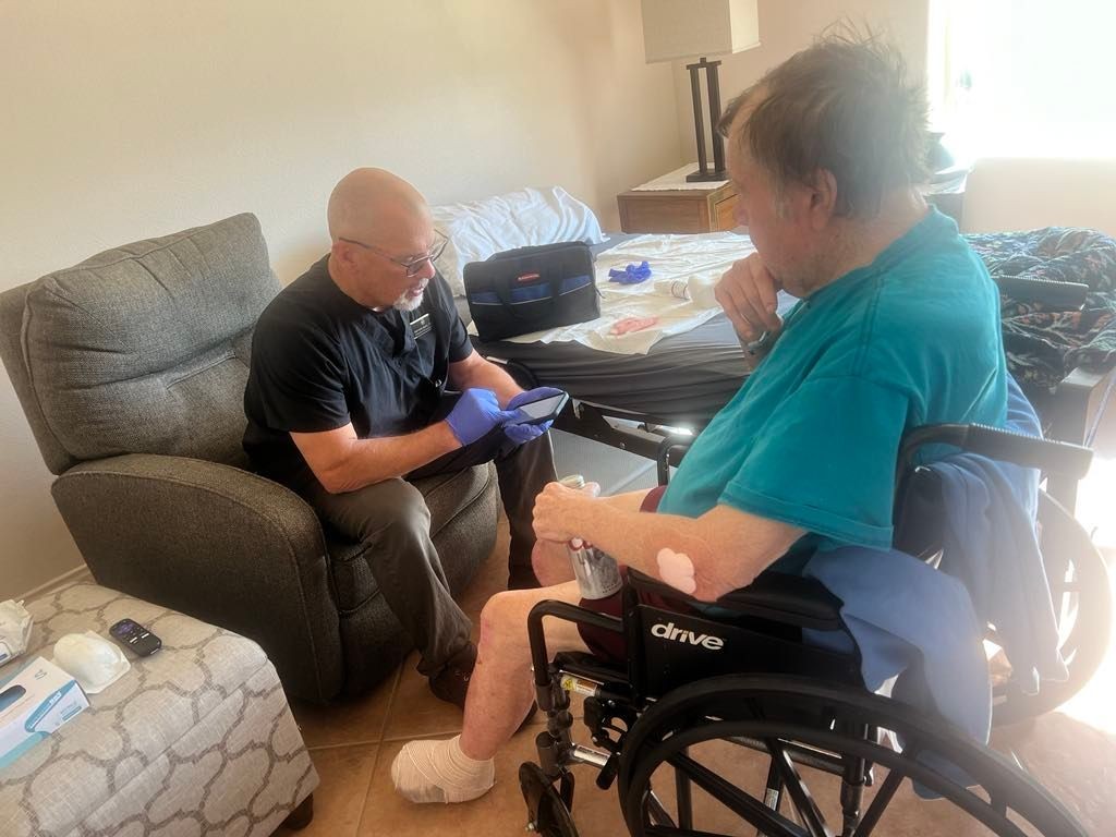 Healthcare worker wearing gloves assists a patient in a wheelchair in a home setting.